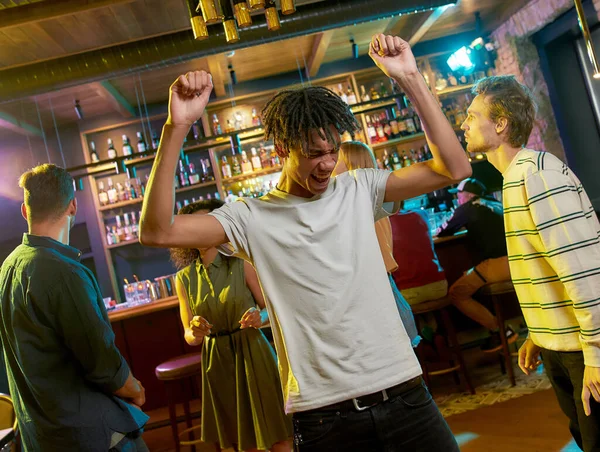 Joven alegre de raza mixta divirtiéndose, bailando con amigos en la fiesta en el bar — Foto de Stock