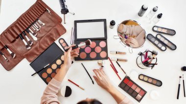 İlham. Genç bir kadın, makyaj yapan bir sanatçı, masada oturuyor. Makyaj yapan yakın plan kadın elleri. Kozmetik reklam konsepti