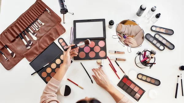 İlham. Genç bir kadın, makyaj yapan bir sanatçı, masada oturuyor. Makyaj yapan yakın plan kadın elleri. Kozmetik reklam konsepti