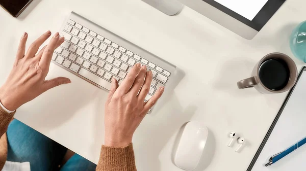 Manos de una señora madura sentada frente a un PC escribiendo en un teclado — Foto de Stock