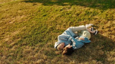 Yaz parkında çimenlerin üzerinde uzanan mutlu lezbiyen çift. Kadınlar birbirine bakmayı sever, birlikte dışarıda vakit geçirmeyi.