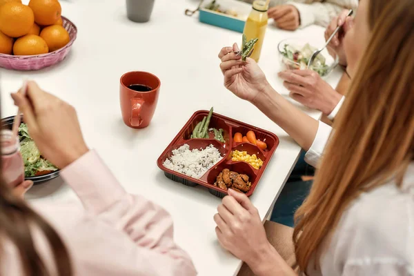 Κοντινό πλάνο ενός υγιούς φαγητού που αποτελείται από λαχανικά και ρύζι τρώγοντας από μια νεαρή γυναίκα που κάθεται σε ένα τραπέζι κατά τη διάρκεια ενός επαγγελματικού γεύματος — Φωτογραφία Αρχείου