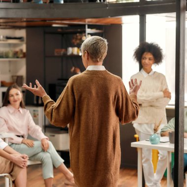 Yetişkin bir bayan patronun modaya uygun kıyafetler ve kısa saç kesimi giyip bir beyin fırtınası sırasında kadın iş arkadaşlarıyla konuşmasının özeti.