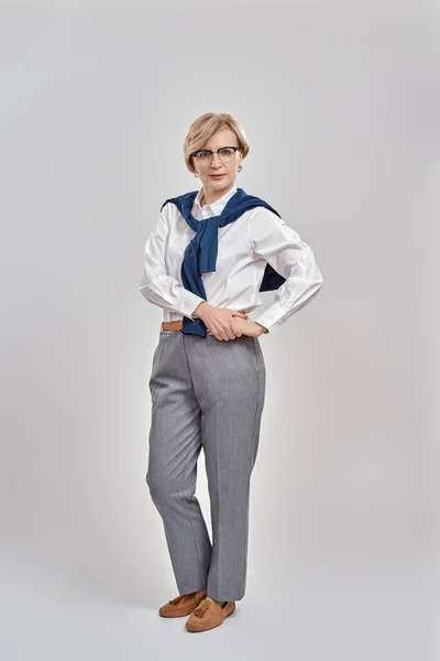 Full length shot of elegant middle aged caucasian woman wearing business attire and glasses looking at camera while posing, standing isolated over grey background —  Fotos de Stock