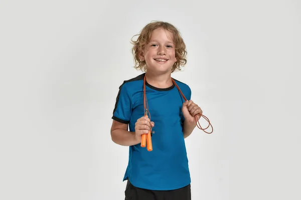 Happy little sportive boy child in sportswear smiling at camera while posing, standing with jump rope isolated over white background — Foto de Stock