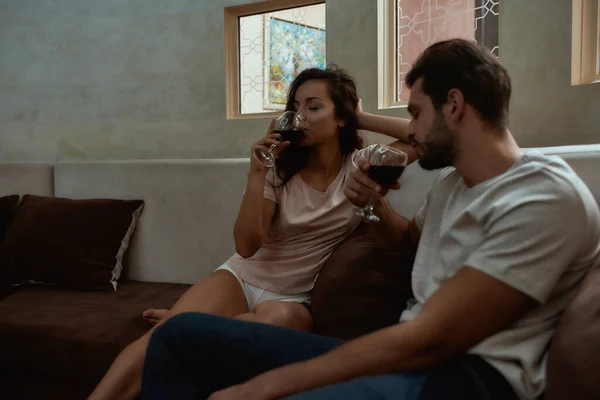 Petreceţi timp împreună. Un cuplu fericit care se relaxează și bea vin în timp ce stă pe canapea acasă — Fotografie, imagine de stoc