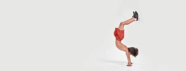 Prise de vue pleine longueur du petit garçon sportif enfant en short sautant, montrant la force et la flexibilité isolé sur fond blanc — Photo