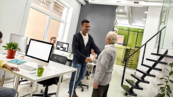 Aged man, senior intern and young guy shaking hands, Young team greeting new worker in the modern office — Stock Photo, Image