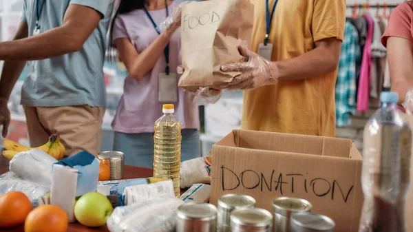 Cropped shot of male and female volunteers packing food donation for needy people, Young team working in charitable foundation — Foto de Stock