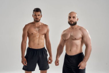 Genç yakışıklı kaslı beyaz adamlar üstsüz duruyor.