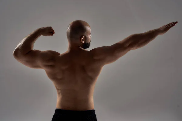 Figura oscurato di giovane bodybuilder muscolare in posa arciere — Foto Stock