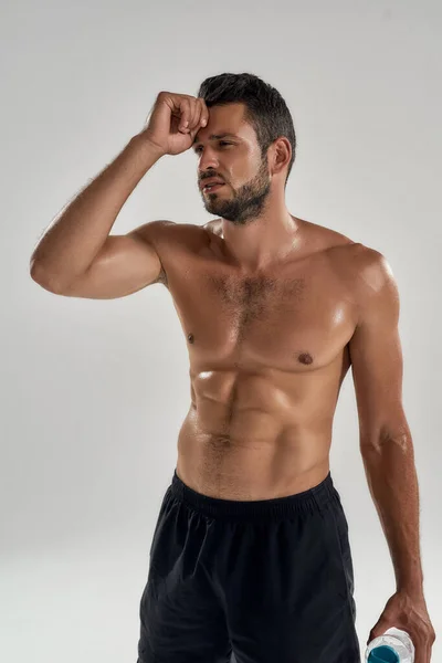 Jovem atleta masculino caucasiano exausto com garrafa de água — Fotografia de Stock