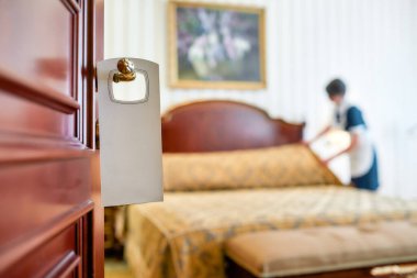 Mükemmel servis. Ön kapısında bir pankartla otel odasını temizleyen üniformalı bir hizmetçi..