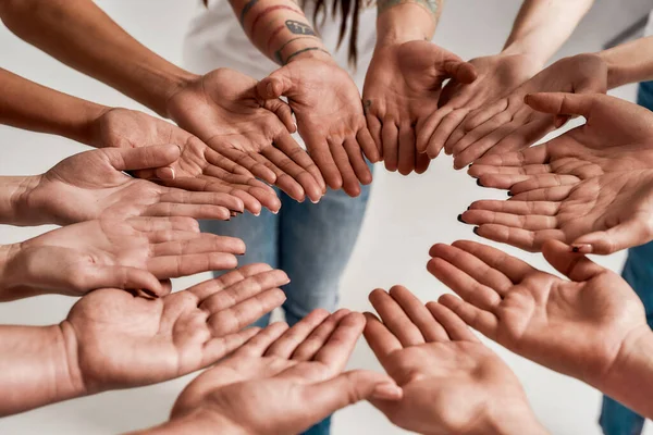 Olika kvinnor håller sina händer öppna handflatan tillsammans, vilket gör en cirkel över grå bakgrund. Begreppet stöd, ras enhet och relationer i samhället — Stockfoto