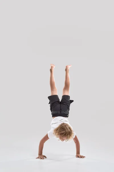 Tiro de comprimento total de criança menino brincalhão de pé em seus braços com as pernas apontando para cima isolado sobre fundo branco — Fotografia de Stock