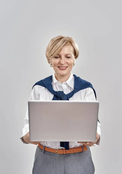 Ritratto di elegante donna caucasica di mezza età che indossa abiti da lavoro con laptop in mano, mentre ha una videochiamata online, isolata su sfondo grigio — Foto Stock