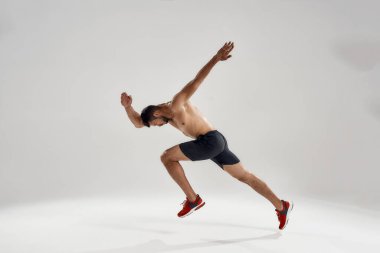 Genç yakışıklı beyaz erkek atlet yan yana koşuyor.