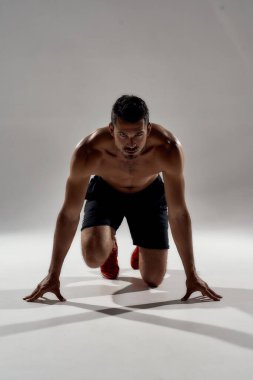 Beyaz tenli yakışıklı sporcu düşük başlangıç pozisyonunda.