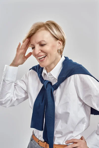 Retrato de una mujer caucásica de mediana edad feliz vestida de negocios tocando su cabeza mientras sonríe, posando aislada sobre un fondo gris —  Fotos de Stock