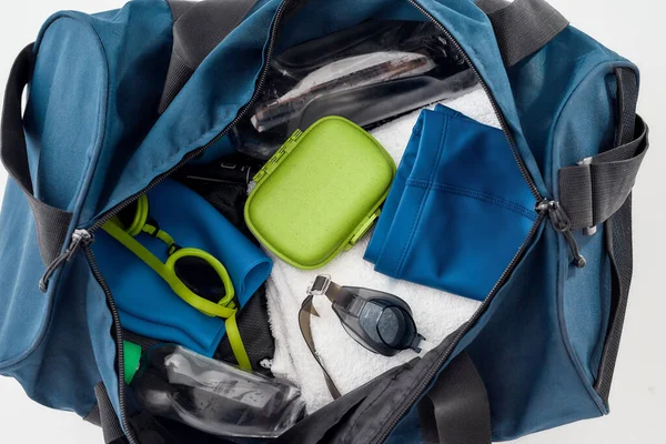 Primer plano de la bolsa de deporte con equipo de natación para los hombres aislados sobre fondo gris. Gafas de baño, sombrero, baúles, toalla y botella de agua —  Fotos de Stock