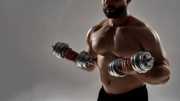 Young muscular sportsman with shirtless torso lifting dumbbells — Stock Photo, Image