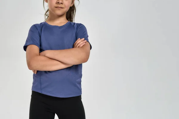 Recortado tiro de niña deportiva en ropa deportiva de pie con los brazos cruzados mientras posando aislado sobre fondo blanco —  Fotos de Stock