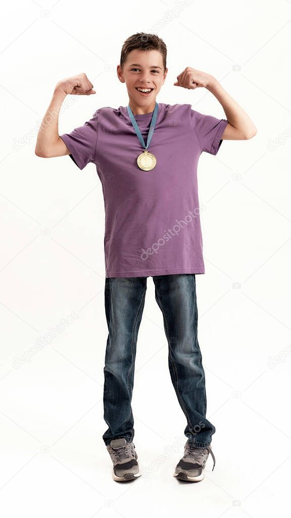 Full length shot of happy teenaged disabled boy with cerebral palsy wearing gold medal, smiling at camera, raising clenched fists, feeling strong, standing isolated over white background