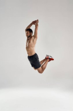 Yüksekten atlayan genç bir erkek sporcu Kaldırılmış ellerle atlıyor