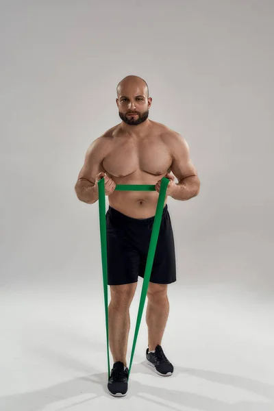 Jovem musculoso caucasiano fisiculturista com faixa elástica — Fotografia de Stock