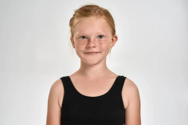 Portré csinos kis vörös hajú sportos lány sportruházat mosolyog a kamera előtt, miközben áll elszigetelt fehér háttér — Stock Fotó