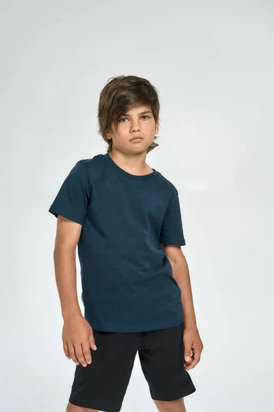 Kleiner sportlicher Junge in Sportbekleidung blickt in die Kamera, während er isoliert vor weißem Hintergrund steht — Stockfoto