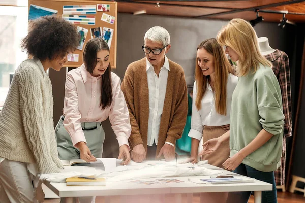 Cinque donne ben vestite di diversa età e razza condividono le loro idee mentre stanno intorno a un tavolo durante un brainstorming — Foto Stock