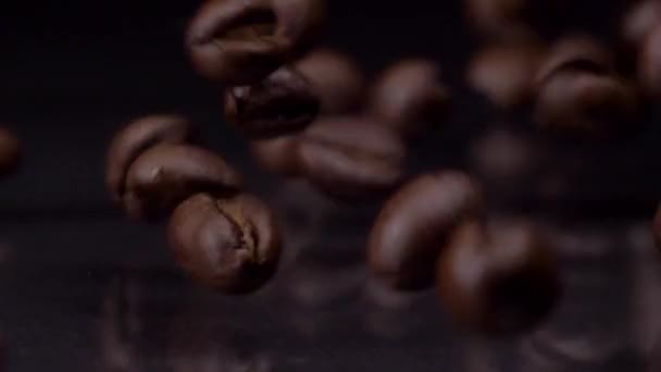 Rich flavor. Slow motion shot of roasted brown coffee beans rolling, falling on dark background. Coffee grains close up 4K video. — Stock Video