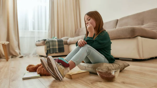 Una linda niña pequeña protagonizada por un gamepad tumbado en sus pies sentado en un piso en medio de una sala espaciosa —  Fotos de Stock