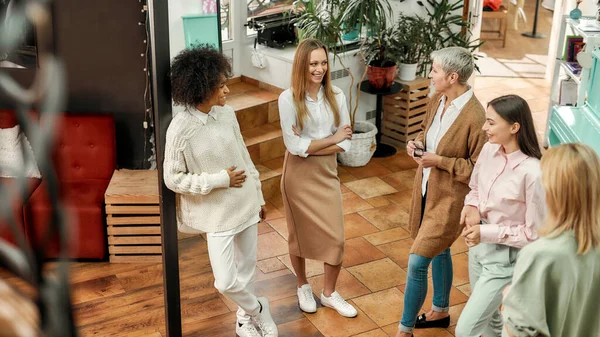 Un grupo de mujeres de diferentes edades y nacionalidades hablando juntas en un gran taller de moda —  Fotos de Stock