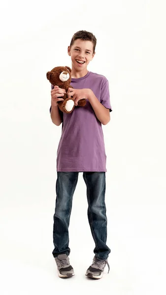 Full length shot of happy teenaged disabled boy with cerebral palsy smiling at camera, holding his teddy bear toy, standing isolated over white background — Stock Photo, Image