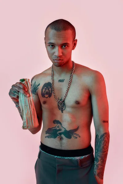 Beba com responsabilidade. Um macho de pele escura com tatuagens em topless segurando uma garrafa em um saco de papel — Fotografia de Stock