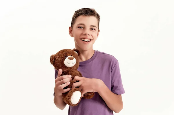 Portrait of happy teenaged disabled boy with cerebral palsy smiling at camera and holding his teddy bear toy, posing isolated over white background — Stock Photo, Image