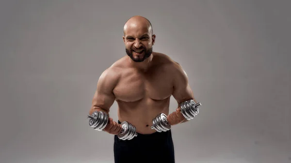 Jovem muscular caucasiano halterofilista segurando halteres — Fotografia de Stock