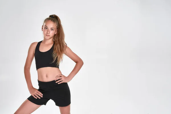 Retrato de niña linda deportiva en ropa deportiva negro mirando a la cámara mientras posando aislado sobre fondo blanco — Foto de Stock