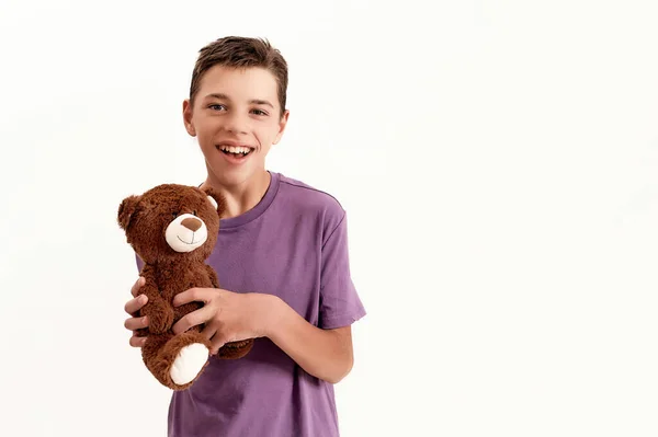 Retrato de niño discapacitado adolescente feliz con parálisis cerebral sonriendo a la cámara y sosteniendo su juguete de oso de peluche, posando aislado sobre fondo blanco — Foto de Stock