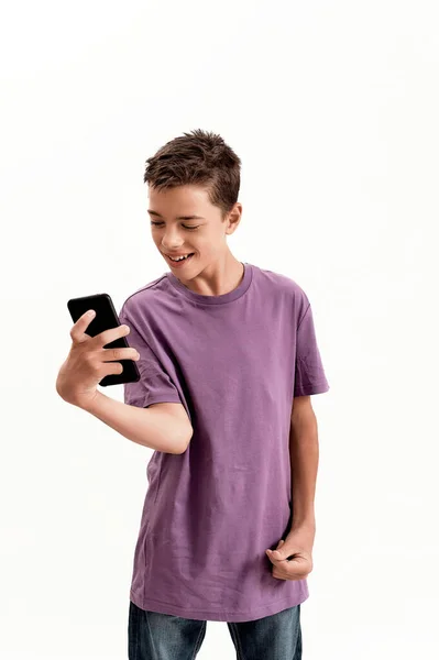 Niño discapacitado adolescente con parálisis cerebral que parece feliz mientras sostiene y usa un teléfono inteligente, posando aislado sobre un fondo blanco — Foto de Stock