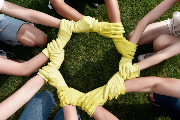 Harika bir takım çalışması. Koruyucu lastik eldiven giyen bir grup gönüllü bir parkı temizlerken ellerini birleştiriyor. — Stok fotoğraf