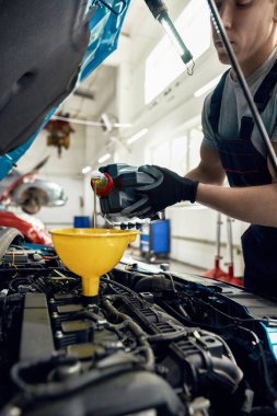Genç Kafkasyalı işçi motor yağını değiştiriyor