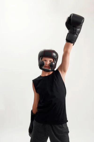 Niño discapacitado con síndrome de Down con guantes de boxeo y casco, mirando a la cámara, levantando el brazo, sintiéndose fuerte mientras posa aislado sobre fondo blanco — Foto de Stock