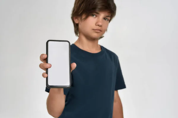 Niño pequeño deportivo en ropa deportiva sosteniendo, mostrando teléfono inteligente con pantalla en blanco, de pie aislado sobre fondo blanco —  Fotos de Stock