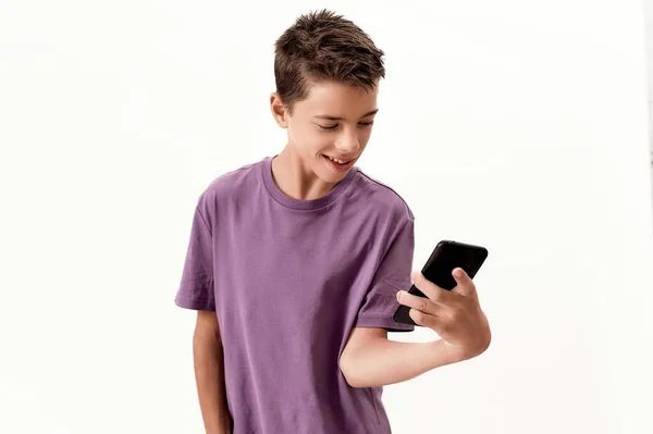 Adolescente deficiente menino com paralisia cerebral olhar feliz enquanto segurando e usando smartphone, posando isolado sobre fundo branco — Fotografia de Stock