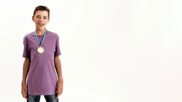 Ritratto di felice adolescente disabile con paralisi cerebrale che indossa medaglia d'oro, sorridente alla macchina fotografica mentre in piedi isolato su sfondo bianco — Foto Stock