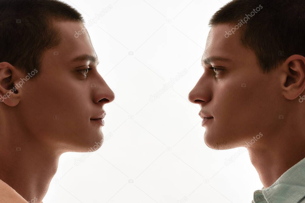 Family relationships concept. Silhouetted portrait of two young caucasian twin brothers looking at each other while standing face to face