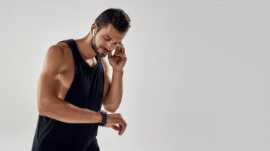 Genç yakışıklı beyaz atlet akıllı saate bakıyor.